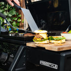 Primer plano de espátulas preparando hamburguesas con queso y huevo sobre la plancha del asador Napoleon Freestyle 24 - Ferretería La Palma - 1890000