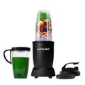 Vista frontal de la licuadora personal Nutribullet Pro de 900W con frutas, almendras y vegetales en el vaso principal, un licuado verde en el vaso con asa, tapa portátil y anillo de comodidad - Almacén La Palma - 1690015