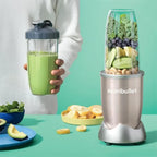 Persona sosteniendo un vaso con batido verde al lado de la licuadora Nutribullet Pro 900W con ingredientes frescos sobre fondo menta - Ferretería La Palma - 1690013