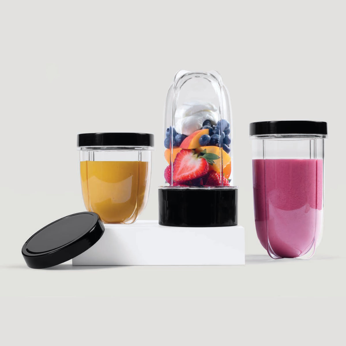 Kit de accesorios Magic Bullet con vasos llenos de batidos y un vaso con frutas frescas sobre fondo blanco - Ferretería La Palma - 1690007