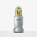 Licuadora personal Nutribullet Original 600W en color plateado con vaso lleno de rodajas de kiwi, aguacate y fresas frescas sobre fondo blanco - Ferretería La Palma - 1690080