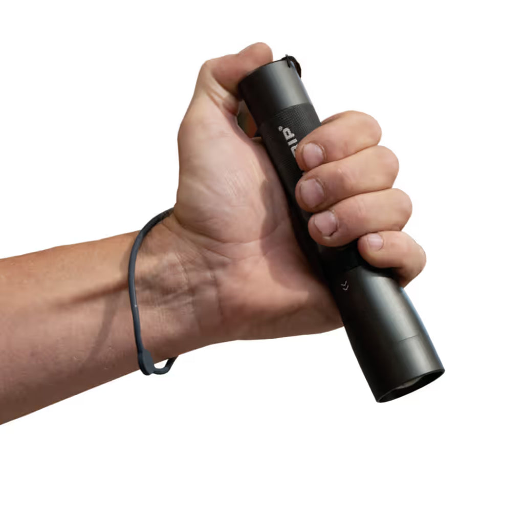 Mano sujetando la linterna LED Scangrip FLASH 600 R mostrando su ergonomía y correa de seguridad integrada para la muñeca - Ferretería La Palma - 1870006