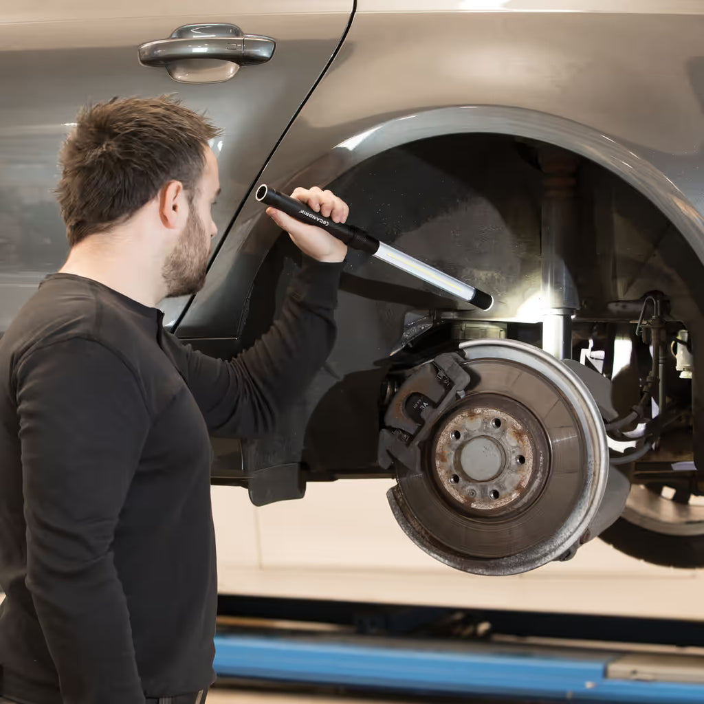 Mecánico iluminando el sistema de frenos y la suspensión en el paso de rueda de un coche con la lámpara de inspección LED tipo barra Scangrip LINE LIGHT C+R - Ferretería La Palma - 1870007