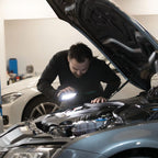 Mecánico inspeccionando el motor de un automóvil en un taller utilizando el reflector industrial LED Scangrip STAR encendido - Ferretería La Palma - 1870001