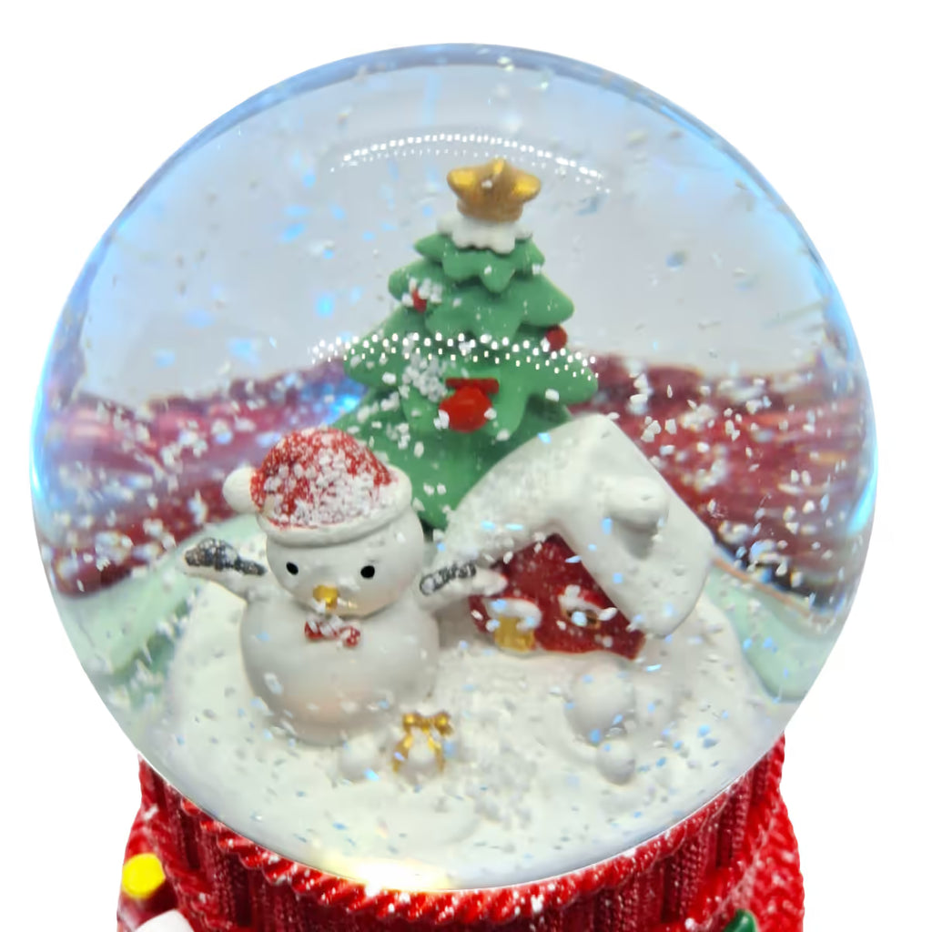 Primer plano de la escena navideña nevada con Muñeco de Nieve, casa y árbol decorado dentro de la esfera de cristal Starlights sobre un fondo blanco - Ferretería La Palma - 180001