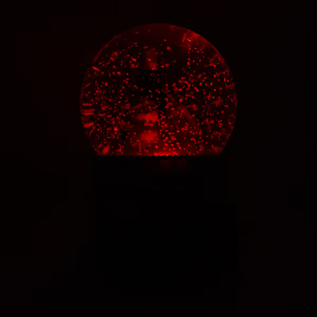 Vista frontal de la bola de nieve musical navideña Starlights Muñeco de Nieve mostrando luz en color rojo en un fondo oscuro - Ferretería La Palma - 1800001