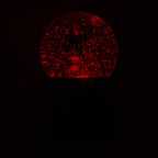 Vista frontal de la bola de nieve musical navideña Starlights Muñeco de Nieve mostrando luz en color rojo en un fondo oscuro - Ferretería La Palma - 1800001