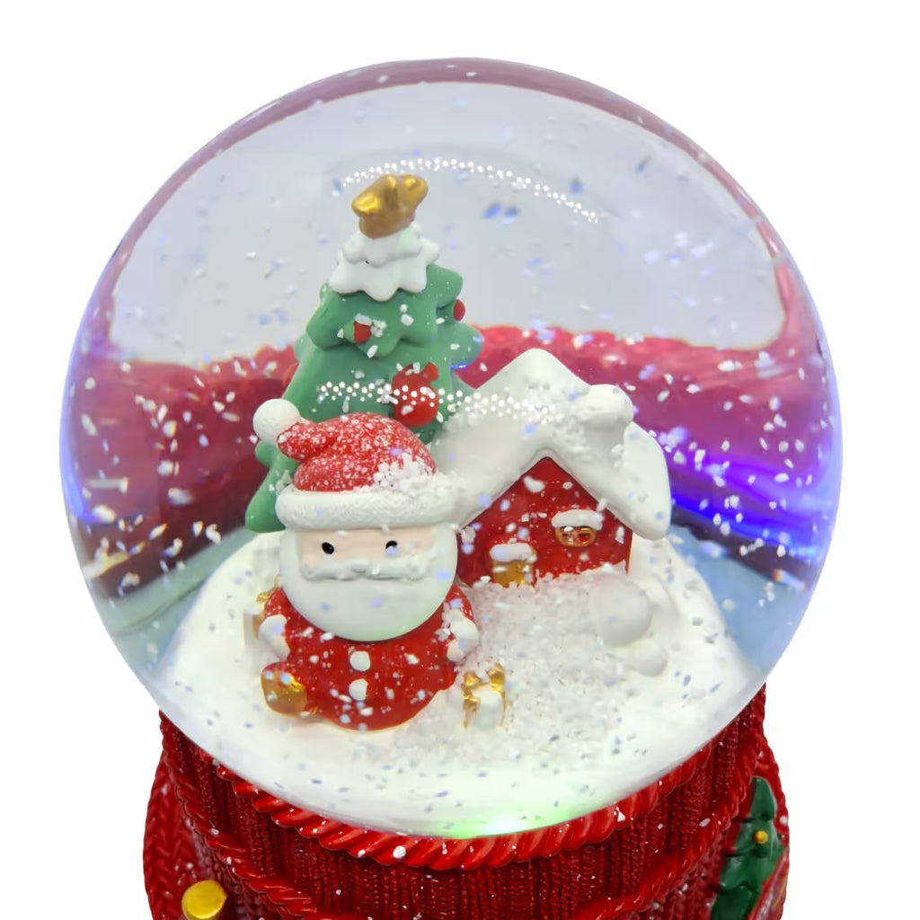 Primer plano de la escena navideña nevada con Santa Claus, casa y árbol decorado dentro de la esfera de cristal Starlights sobre un fondo blanco - Ferretería La Palma - 180000