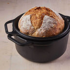 Vista superior en perspectiva del Combo Cooker 2 en 1 Victoria de 5.7 litros en hierro fundido esmaltado con un pan artesanal recién horneado sobre una superficie clara - Ferretería La Palma - 1050079