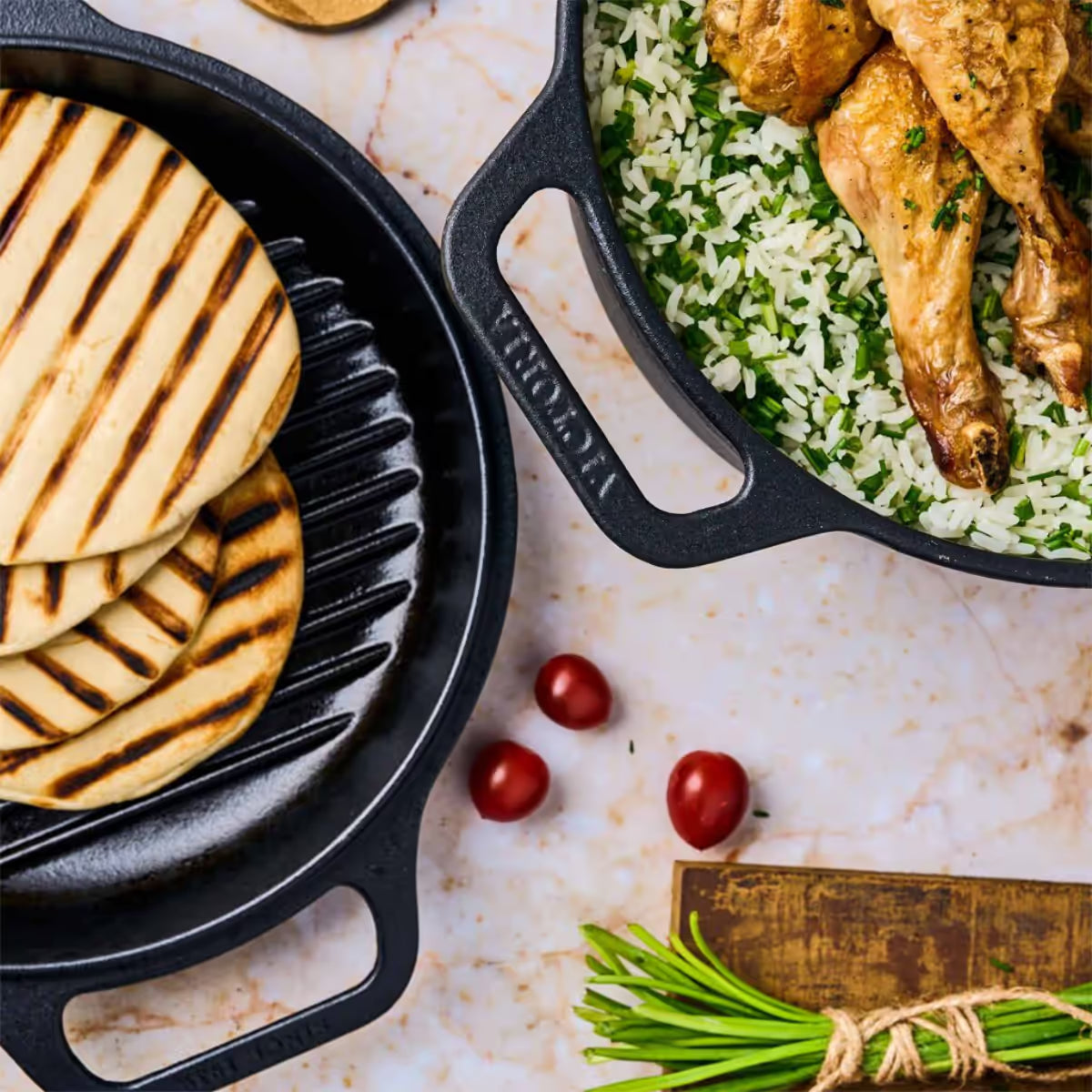 Vista superior del Combo Cooker 2 en 1 Victoria de 5.7 litros en hierro fundido esmaltado con pollo asado sobre arroz en la olla y panes asados en la tapa tipo grill sobre una superficie clara - Ferretería La Palma - 1050079