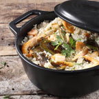 Vista en perspectiva del horno holandés Victoria de 3.8 litros en hierro fundido esmaltado con un arroz de mariscos, camarones y mejillones sobre una mesa de madera rústica - Ferretería La Palma - 1050044