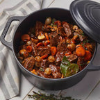 Vista superior en perspectiva del horno holandés Victoria de 6.6 litros en hierro fundido esmaltado con un estofado de carne, champiñones, zanahorias y cebollitas sobre una mesa de madera blanca - Ferretería La Palma - 1050085
