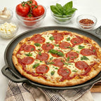 Vista en perspectiva de la plancha redonda para pizza Victoria de 30 cm en hierro fundido esmaltado con una pizza de pepperoni y albahaca, acompañada de bowls con ingredientes sobre una mesa blanca - Ferretería La Palma - 1050087