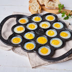 Vista superior en perspectiva de la provoletera Victoria en hierro fundido esmaltado con huevos de codorniz preparados y sazonados, acompañada de pan sobre una superficie clara - Ferretería La Palma - 1050076
