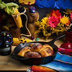 Vista en perspectiva del sartén de hierro fundido Victoria de 25 cm ambientado con pan de muerto, calaveras decorativas, mazorcas de maíz y flores sobre un mantel colorido - Almacén La Palma - 1050097