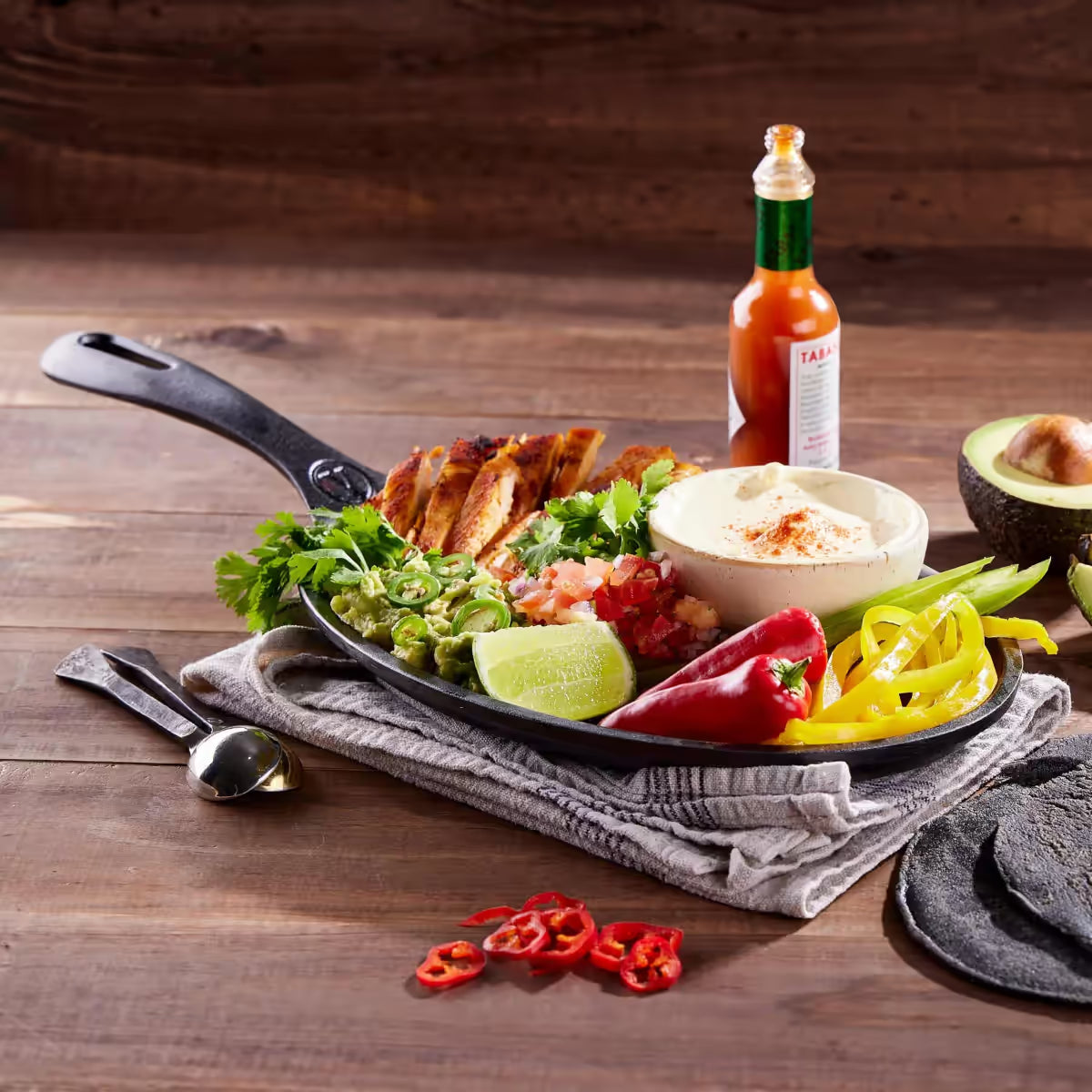 Sartén para fajitas Victoria esmaltado de 24 cm con tiras de pollo asado, guacamole, pimientos y crema, acompañado de tortillas negras y salsa picante - Ferretería La Palma - 1050050