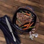 Vista cenital del sartén grill cuadrado Victoria de 25 cm en hierro fundido curado con doble asa lateral con un corte de carne T-bone, zanahorias baby, ajos y romero fresco - Ferretería La Palma - 1050069