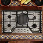 Vista cenital del sartén grill cuadrado Victoria de 25 cm en hierro fundido curado sobre una estufa de gas en un ambiente de cocina tradicional - Ferretería La Palma - 1050026