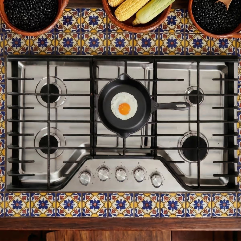 Sartén de hierro fundido esmaltado Victoria 20cm con huevo frito, colocada sobre estufa de acero inoxidable en cocina rústica decorada - Ferretería La Palma - 1050013