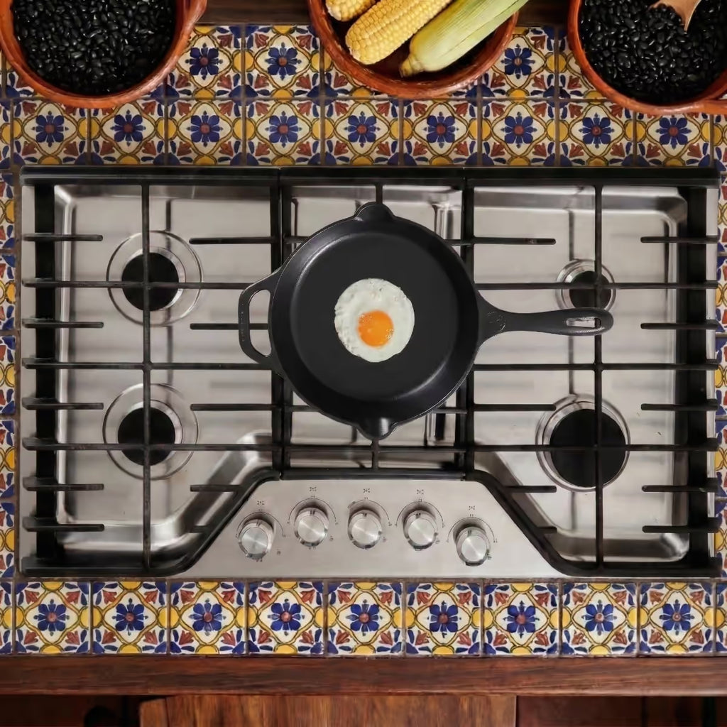 Vista cenital de un sartén de hierro fundido esmaltado Victoria de 25 cm sobre una estufa de acero inoxidable cocinando un huevo - Ferretería La Palma - 1050014