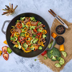 Vista cenital del sartén wok Victoria de 35.5 cm en hierro fundido curado con un salteado de carne, brócoli y pimientos rodeado de ingredientes frescos - Ferretería La Palma - 1050039