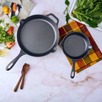 Vista cenital del set de dos sartenes Victoria de 20 cm y 25 cm en hierro fundido esmaltado rodeados de ingredientes frescos sobre una superficie de mármol - Ferretería La Palma - 1050099