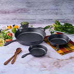 Vista del set de tres sartenes Victoria de 16.5 cm, 20 cm y 25 cm en hierro fundido esmaltado rodeados de ingredientes frescos sobre una superficie de mármol - Ferretería La Palma - 1050098