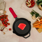Vista cenital del set de sartén redondo Victoria de 23 cm en hierro fundido esmaltado con protector de mango de silicona rojo y raspador de limpieza rodeado de ingredientes frescos - Ferretería La Palma - 1050148