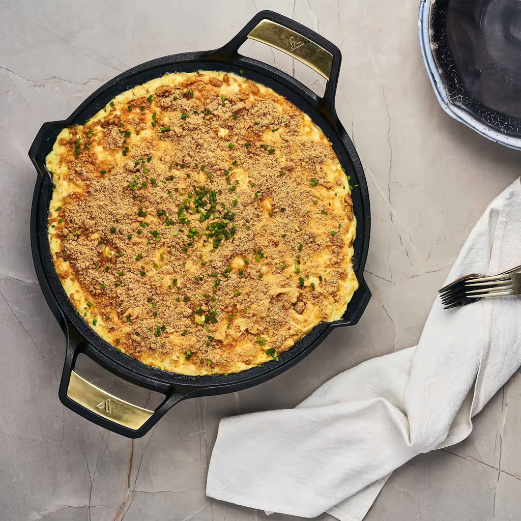 Paellera Victoria Signature 33 cm con un gratinado de pasta y queso espolvoreado con cebollín sobre una superficie de mármol - Ferretería La Palma - 1050093