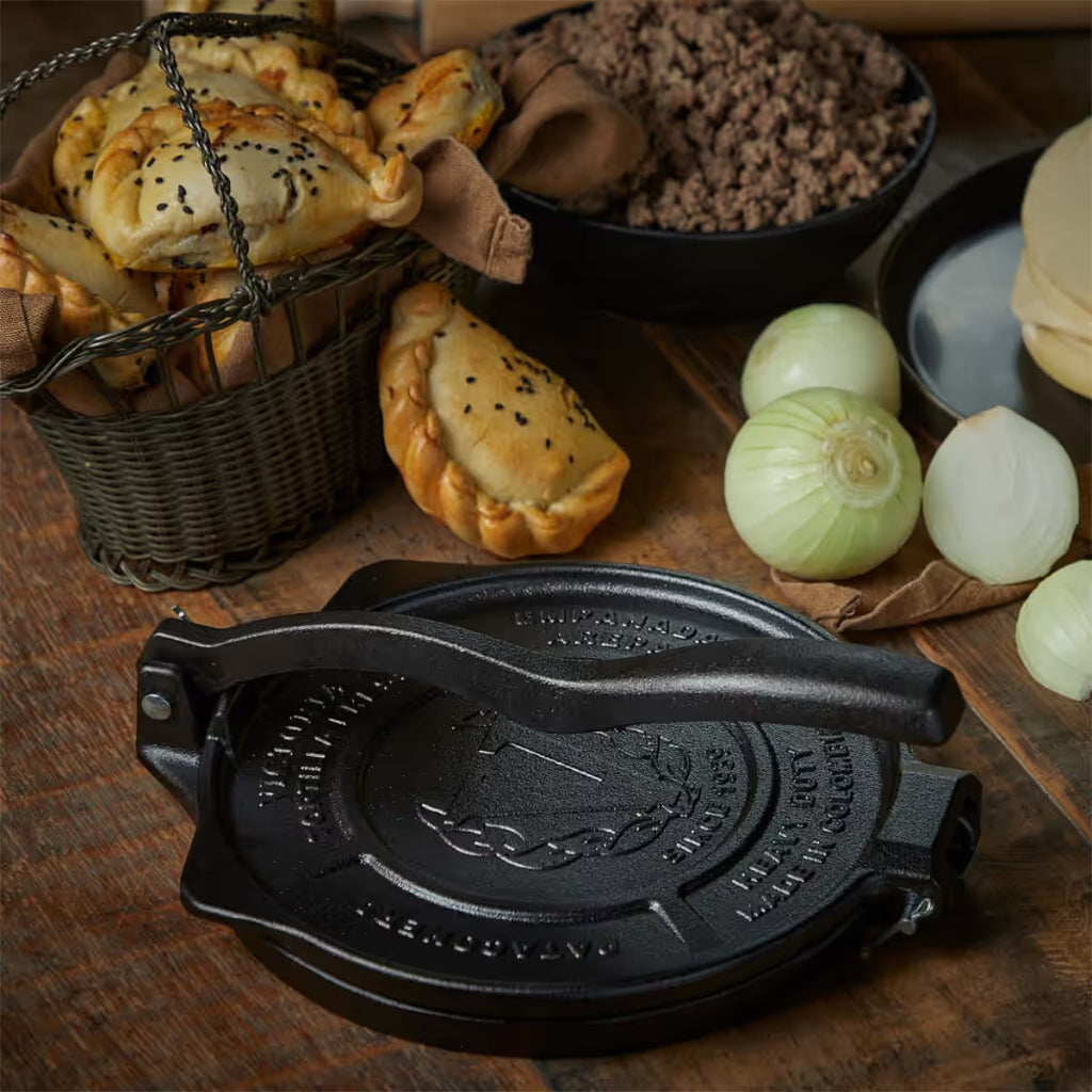 Prensa para empanadas Victoria Heavy Duty 20 cm (8 pulgadas) en mesa rústica con canasta de empanadas horneadas y carne molida - Ferretería La Palma - 1050146
