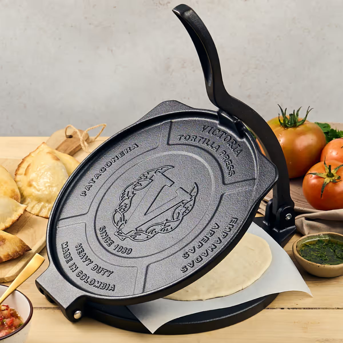Tortillero Victoria Heavy Duty 25 cm abierto con masa de empanada en ambiente de cocina y acompañamiento de tomates - Ferretería La Palma - 1050100